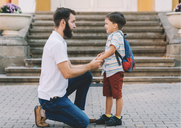 père accroupi qui discute avec son enfant